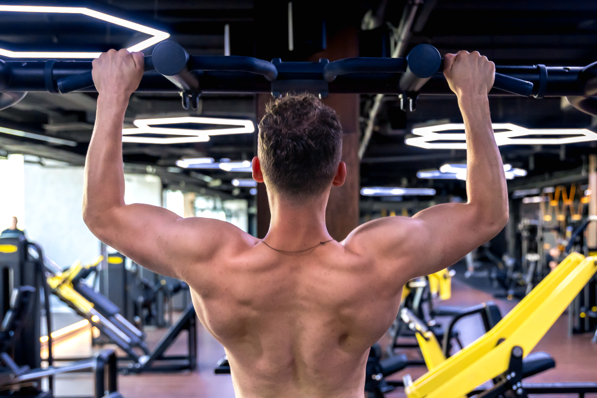 Hombre realizando dominadas en gimnasio mostrando espalda musculada — Rutina Upper Lower 4 días para hipertrofia